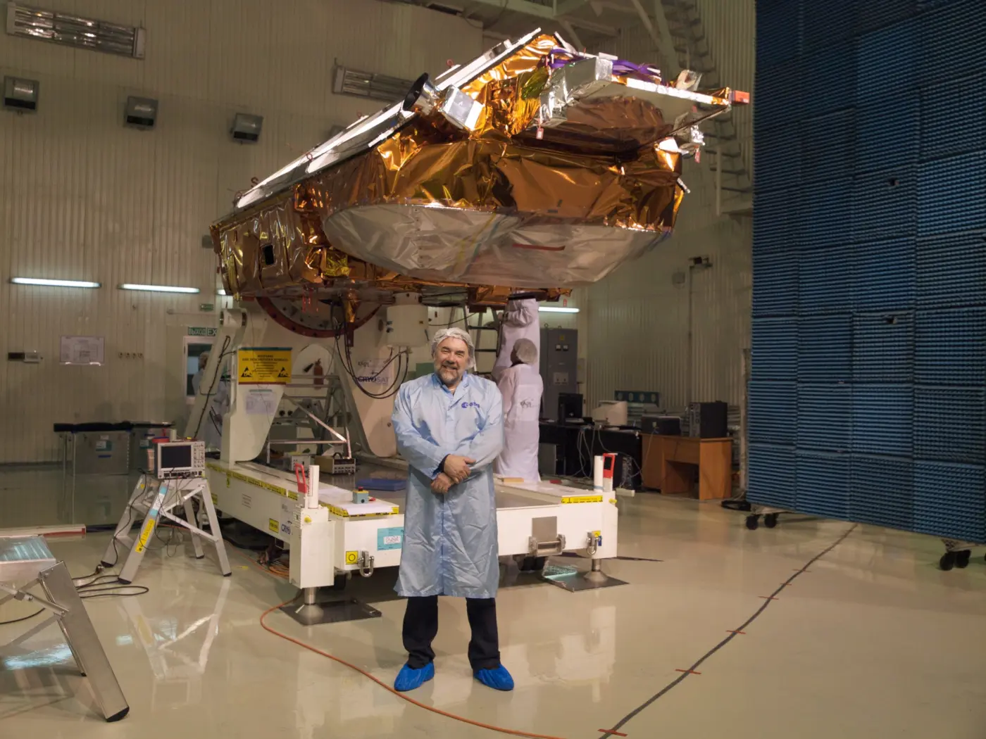 Richard Francis in cleanroom clothing in front of an Earth-observation satellite during integration